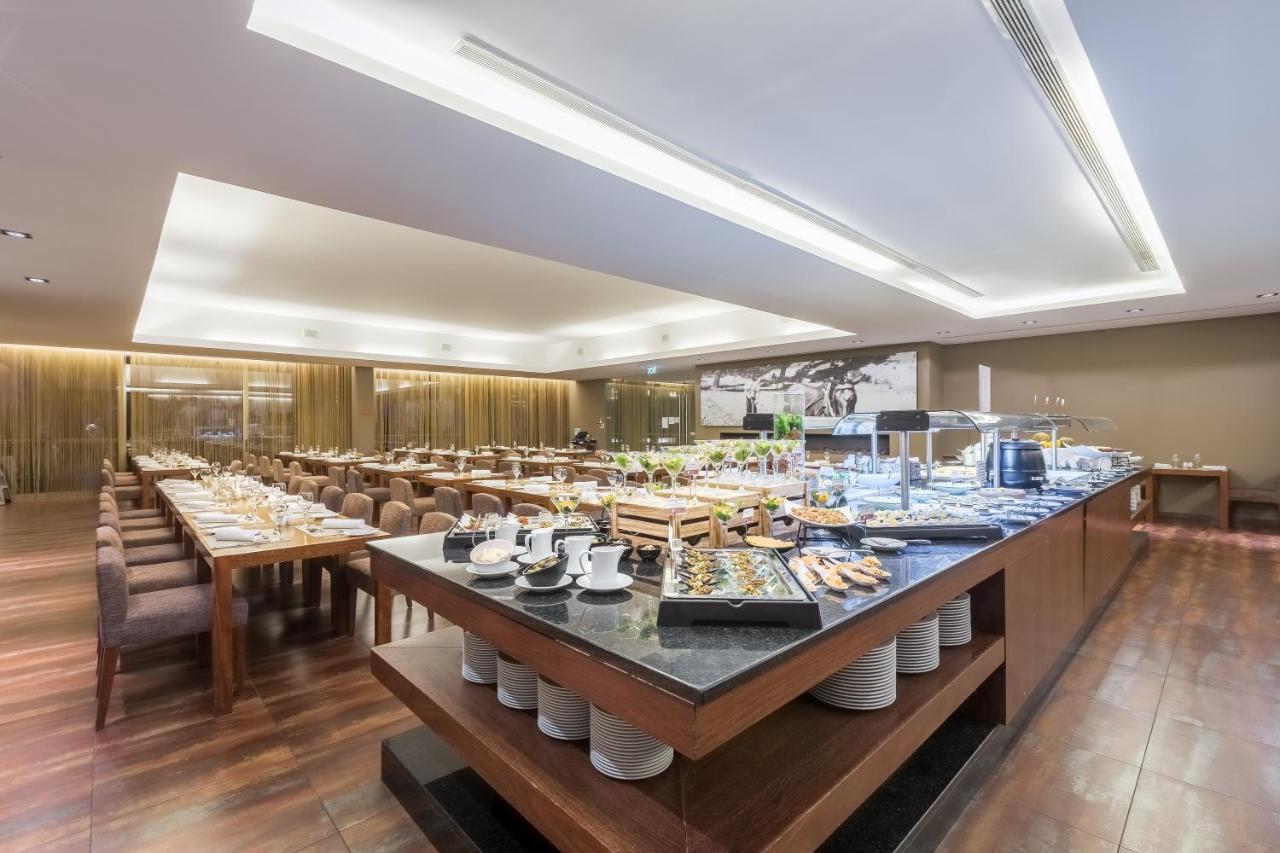 Ap Lago Montargil - Conference & Spa Exterior foto The photo displays a spacious restaurant interior, featuring a well-organized dining area with multiple tables set for patrons. In the center, there is a large buffet station filled with an array of food items. The decor is modern and elegant, with w