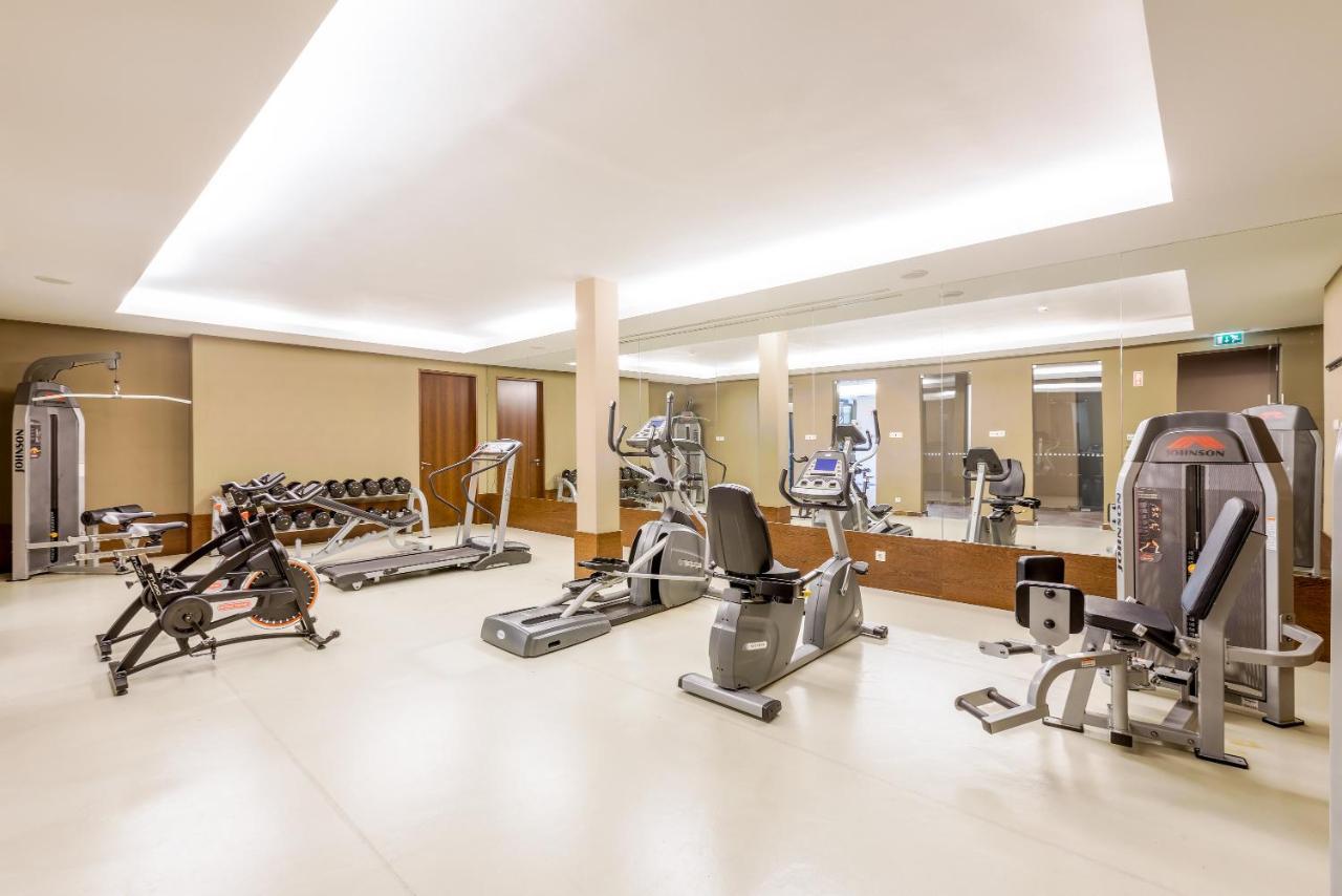 Ap Lago Montargil - Conference & Spa Exterior foto The image shows a modern gym interior featuring various exercise equipment. On the left, there are free weights and weight benches. In the center, there are multiple machines, including a stationary bike and an elliptical. The space is well-lit with 