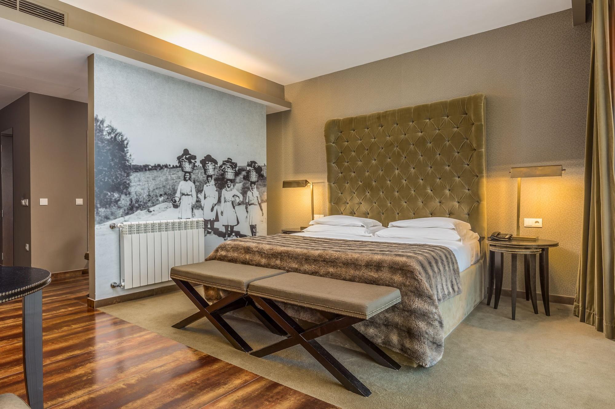 Ap Lago Montargil - Conference & Spa Exterior foto The photo shows a modern hotel room with a large, plush bed that has a tufted, green headboard. The bedding is white with a textured blanket at the foot of the bed. A decorative wall behind the bed features a black and white mural of children in a fi