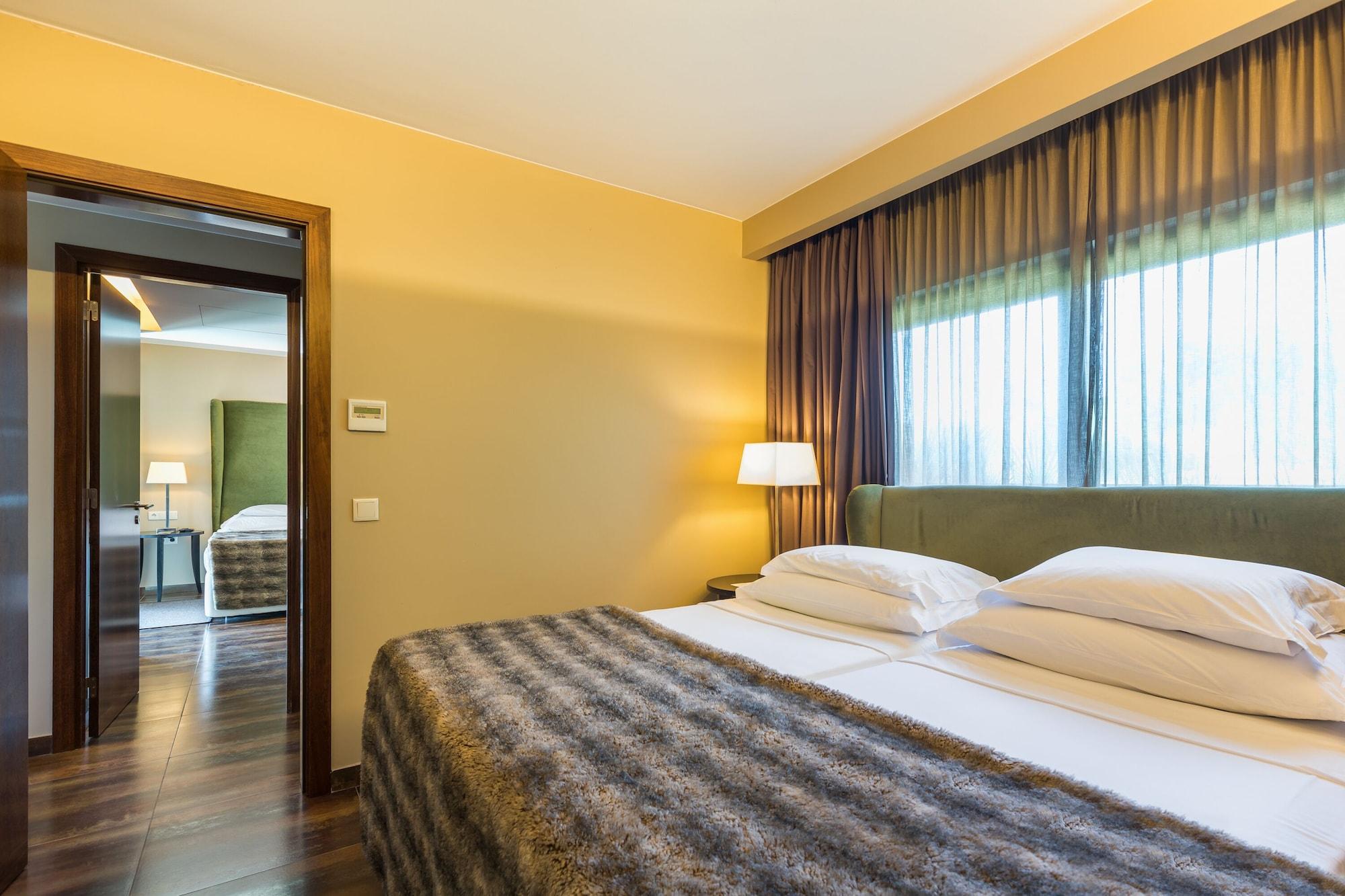 Ap Lago Montargil - Conference & Spa Exterior foto The photo shows the interior of a well-furnished hotel room. It features two beds with white linens and a gray decorative throw on top. The walls are painted a warm yellow, and there are floor-to-ceiling windows covered with dark curtains that allow 