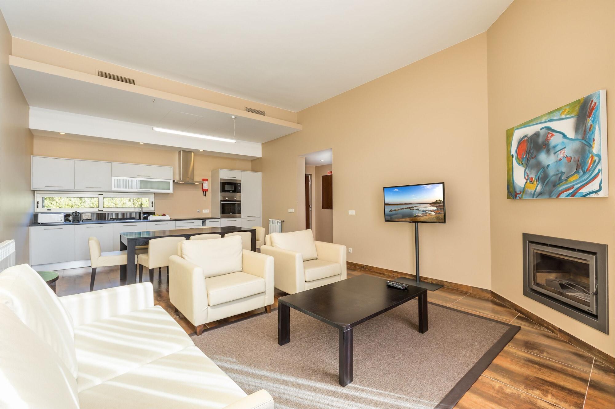 Ap Lago Montargil - Conference & Spa Exterior foto The photo shows a modern, spacious living area with a contemporary design. The room features light-colored walls and wooden flooring. 

In the center, there is a black coffee table surrounded by four white armchairs. A flat-screen TV is mounted on th