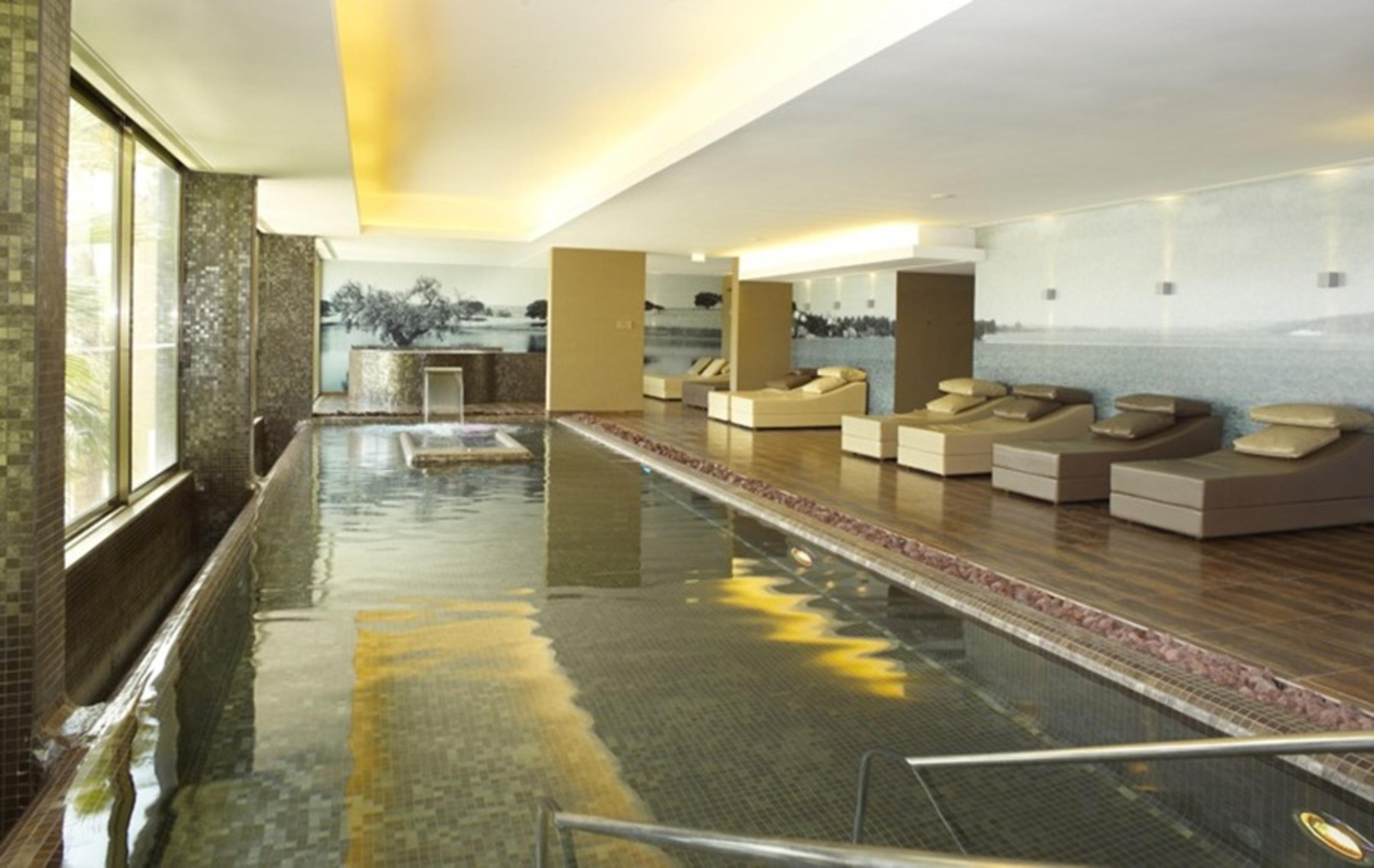 Ap Lago Montargil - Conference & Spa Exterior foto The photo shows a modern, serene spa environment. There is a swimming pool with calm water, reflecting the surrounding decor. Along the sides, there are several comfortable lounge chairs arranged, perfect for relaxation. Large windows allow natural l