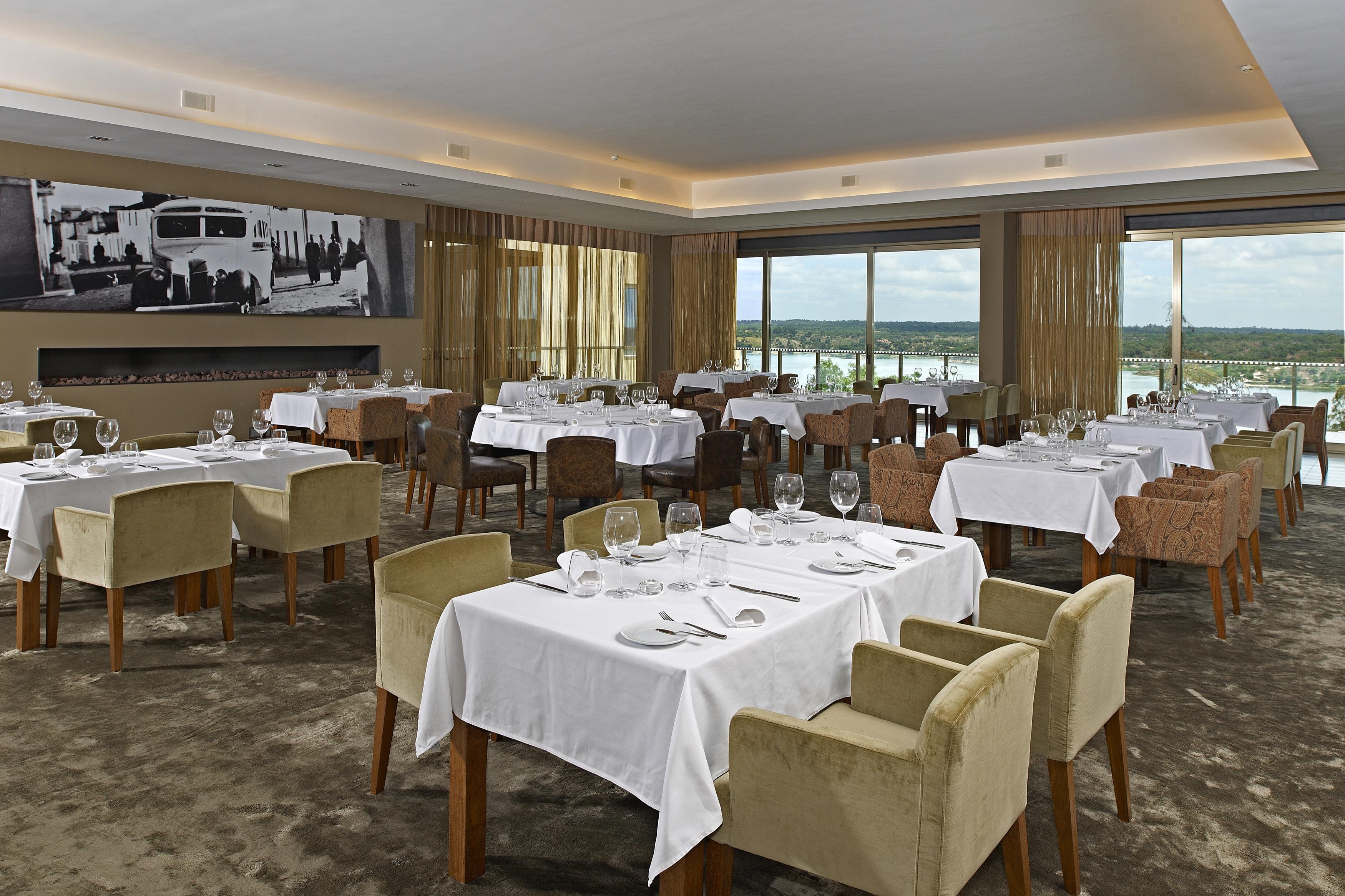 Ap Lago Montargil - Conference & Spa Exterior foto The photo shows an elegant restaurant interior featuring neatly arranged tables with white tablecloths. Each table is set with plates, cutlery, and glasses. The seating includes a mix of upholstered chairs in different colors—some light and others da
